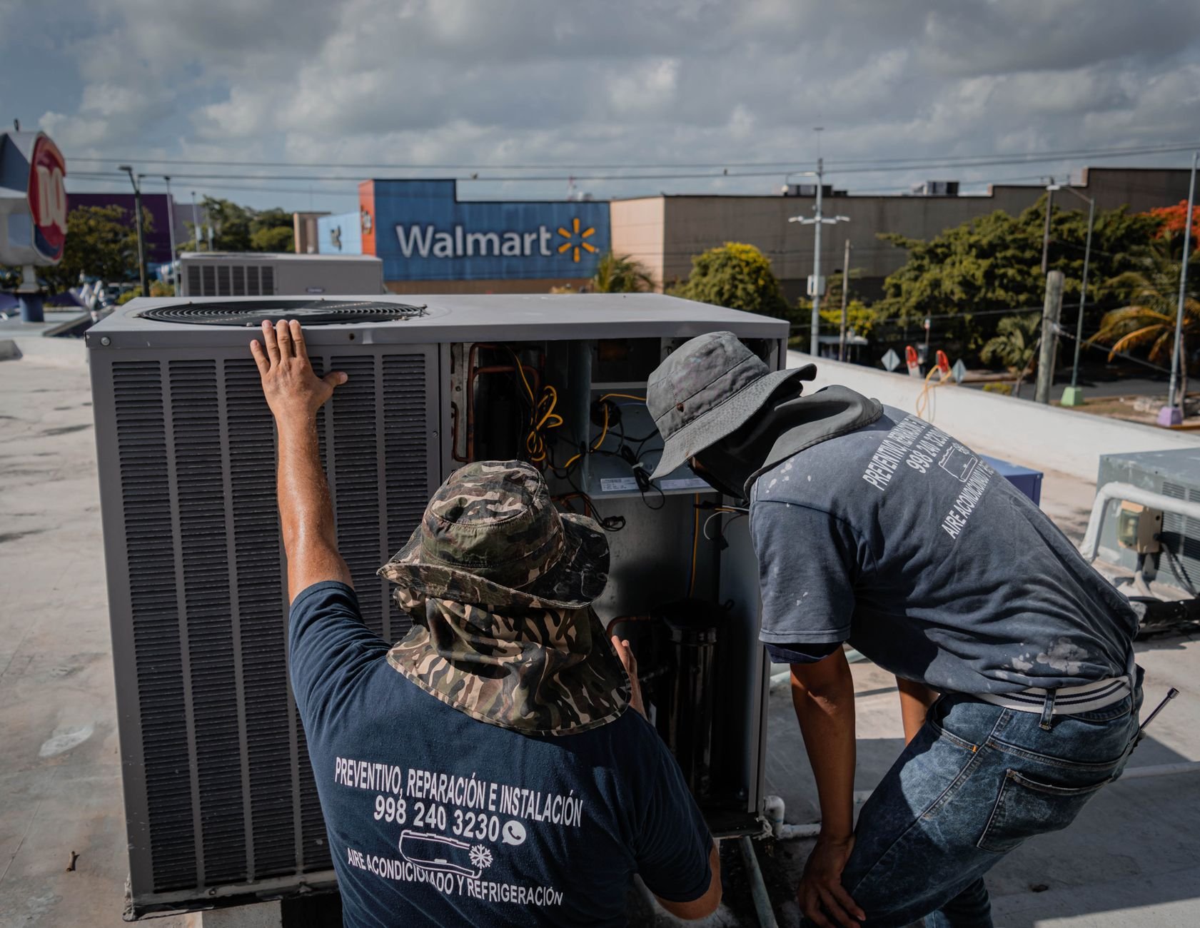 Two HVAC technicians working on a rooftop commercial air conditioning unit.