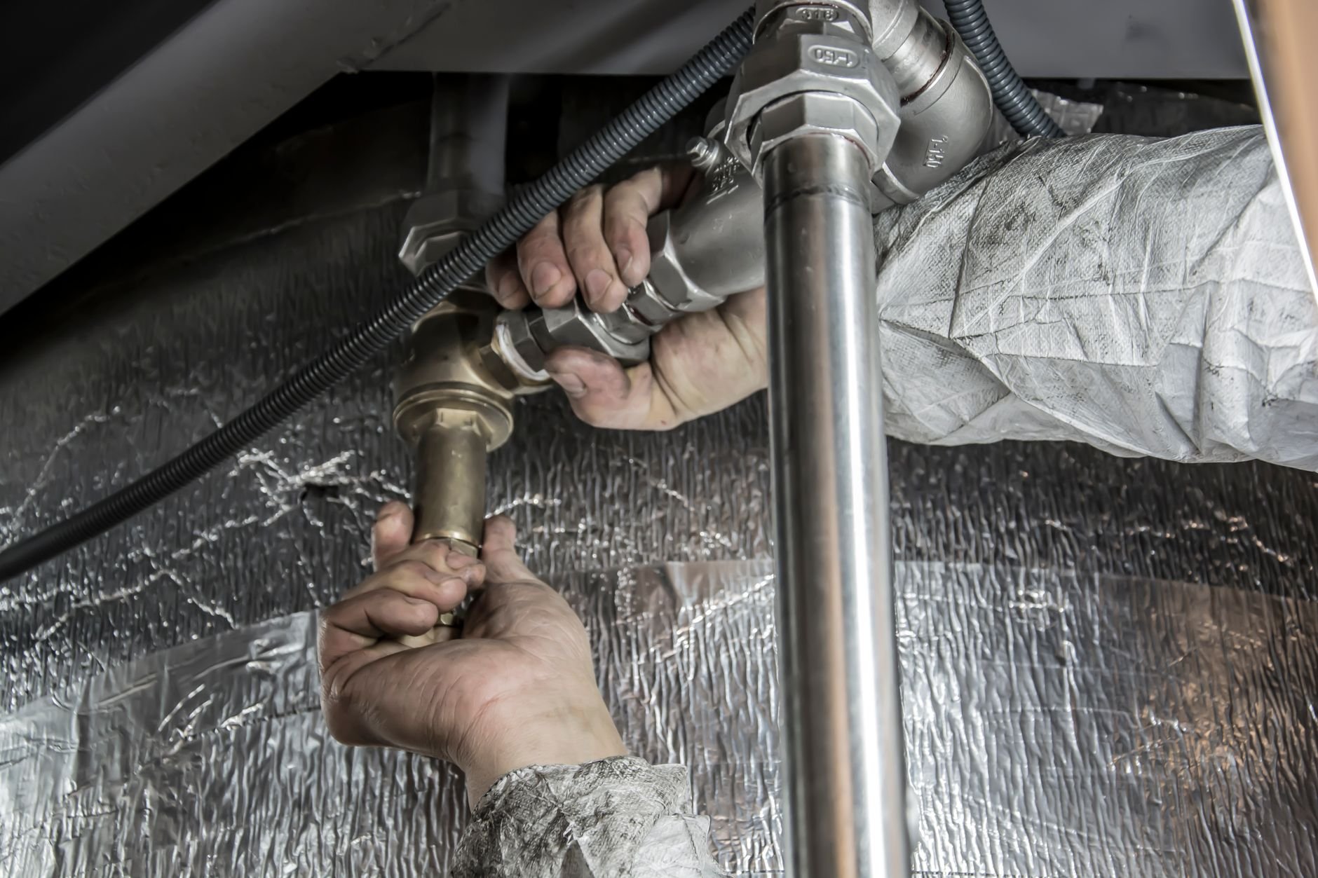 Close-up of a plumber's hands installing steel pipes — skilled trade work.